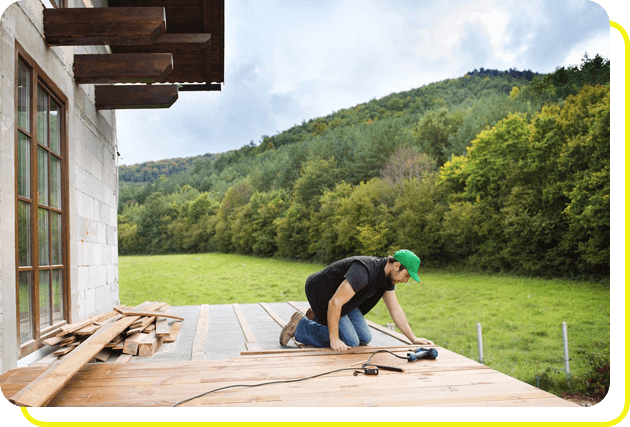 Handyman installing wooden flooring in patio, working with drilling machine